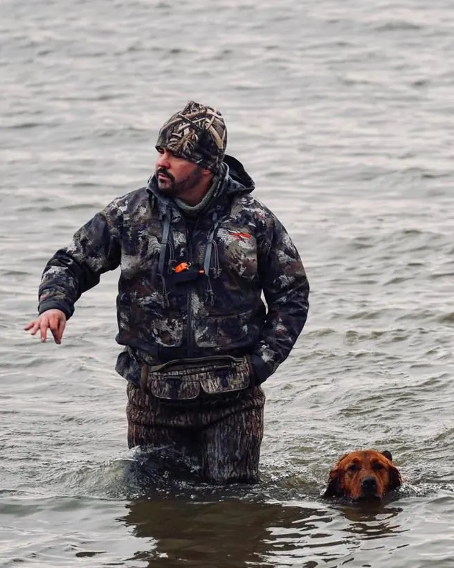 Matthew in waders working his retriever in open water.