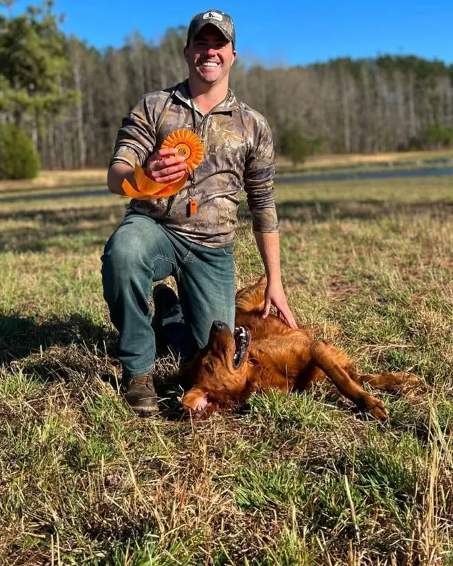 Matthew with his retriever and an AKC ribbon after a field event.